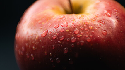 Texture-rich macro photo of a red apple, capturing water droplets on its skin for a fresh and vibrant look.