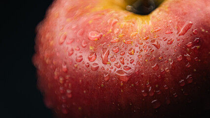 Texture-rich macro photo of a red apple, capturing water droplets on its skin for a fresh and vibrant look.