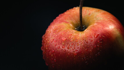 A fresh red apple covered with water droplets, isolated on a black background to emphasize juiciness.
