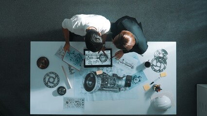 Top down view of skilled engineer working together while looking at jet engine. Aerial view of...