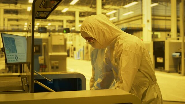 Semiconductor Fabrication Process Lab: Engineers In Cleanroom Protective Suits Inspect A Silicon Wafer, Lithography Exposure In An DUV Scanner. Monitoring of Overlay Accuracy For Production