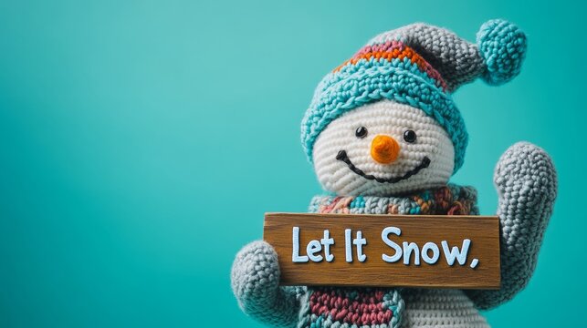 Smiling crochet snowman holding let it snow sign on turquoise background