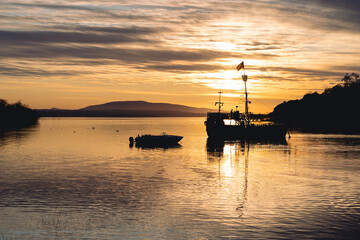 Silhouette of boat at colorful dawn by the lake