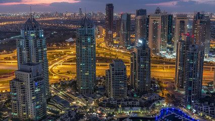 Fototapeta premium Dubai Marina skyscrapers and jumeirah lake towers view from the top aerial night to day timelapse in the United Arab Emirates.