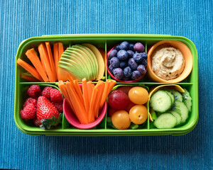 A vibrant snack box for kids, showcasing fruit slices, veggie sticks with hummus, and vegan sandwiches in a playful container, ai.