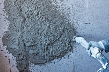 Plasterer using and operating sprayer mortar equipment machine for spraying mortar wall and...