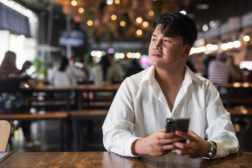 Portrait of Handsome Young Asian Man Sitting in Coffee Shop Restaurant