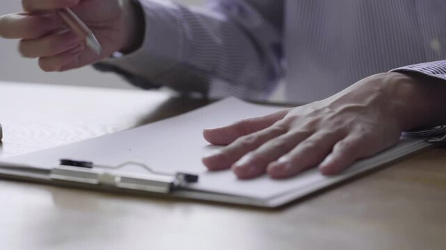 消しゴムで書類の文字を消す女性の手元