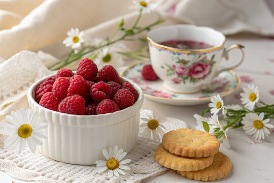 Vibrant Raspberries in White Bowl with Daisies, Vintage Teacup, and Cookies – Dreamy Breakfast Scene in Soft Pastel Tones