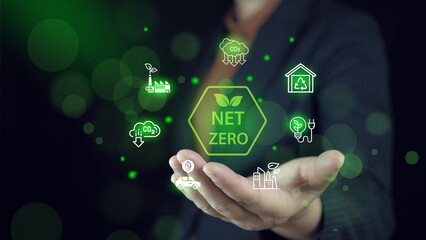 Businessman interacting with holographic icons depicting net zero, eco-friendly, and renewable...