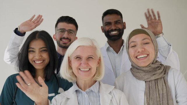 Happy joyful smiling Diverse medical group of doctors and nurses looking at camera and waving 
They exude teamwork and professionalism in a healthcare setting. Multiethnic doctors greeting 