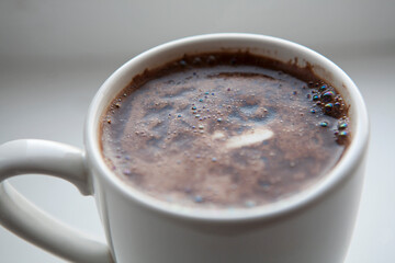 white cup with aromatic coffee on a table with a white background 