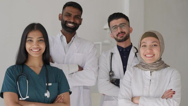 Professional multiethnic asian medical staff looking at camera in modern equipped lab. Diverse team of indian scientists in white coats smiling at camera working together in hospital laboratory