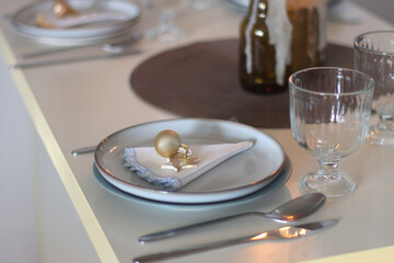 Table set for Christmas meal with plates, glasses, holiday decorations, lit candles and wine. Selective focus.
