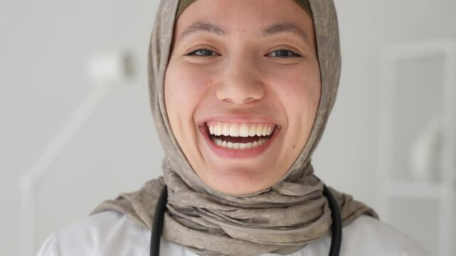 Portrait, medical professional and confident, happy and proud Islamic person woman in hijab or surgeon toothy smiling laughing. Medical intern student. Arabian or Turkish lady doctor 