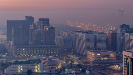 Abu Dhabi city skyline with skyscrapers before sunrise from above night to day timelapse