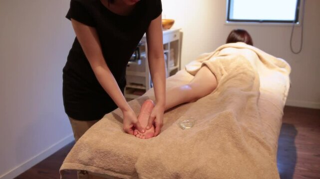セラピストに足裏をマッサージされる女性の顔ヨリ