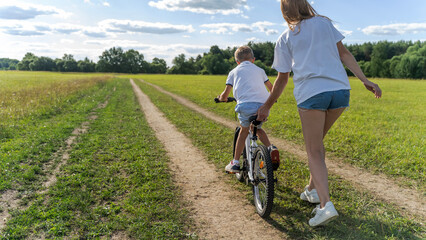 woman teaching boy to ride a bike in the park