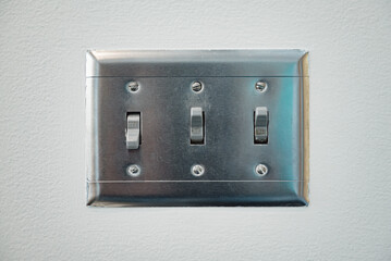 Toggle light switches in on-off mode. The electrical light switches is mounted on the white wall inside a house.