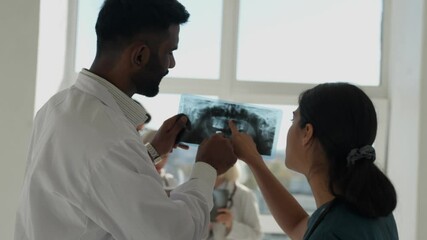 Dentist Doctors Looking At Teeth Xray Using scan paper. Indian doctors watching at dental x-ray plate at clinic, asian doctors dentists discussing about teeth treatment 