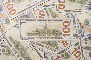 A US 100 dollar bill on top of a pile of scattered dollar bills, currency, texture and background.