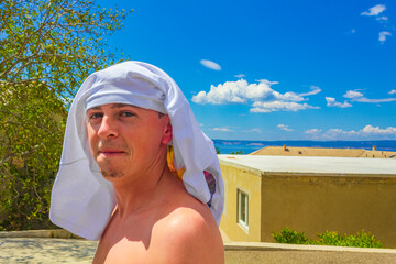 Man in summer at the sea with shirt on head.