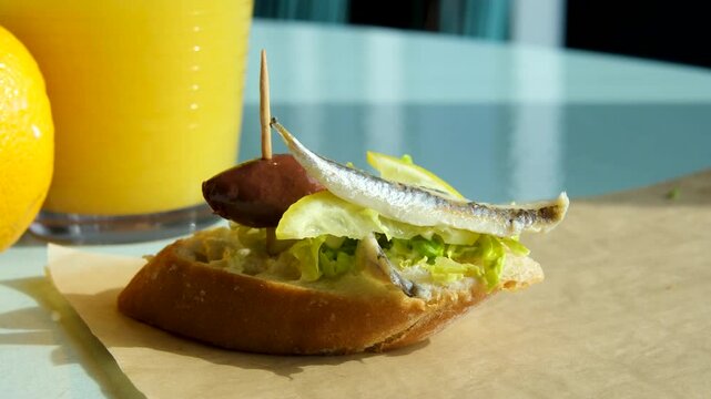 herring and olive sandwich with a slice of lemon avocado orange juice morning onion, pickles on wooden desk close-up, holland Amsterdam cafe. Traditional hollandian fish sandwich Open Faced 
