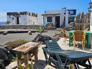 Un petit coin de détente rustique et charmant avec des chaises en osier, des tables en bois brut...