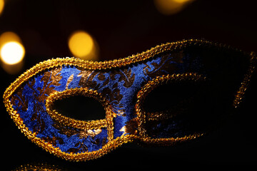Beautiful blue carnival mask on black background, closeup. Bokeh effect