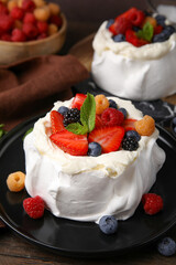 Pavlova cake (meringue dessert) with whipped cream, fresh berries and mint on table, closeup