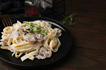 Delicious pasta with mushrooms on wooden table, closeup. Space for text