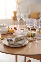 Stylish table setting with beautiful dishware and autumn decor in dining room