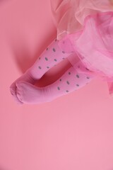 Child wearing tights on pink background, top view. Space for text