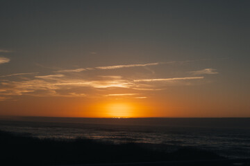 A serene sunset at dusk over the ocean with warm golden tones, soft clouds, and an open sky. Nature background with space for adding text or designs