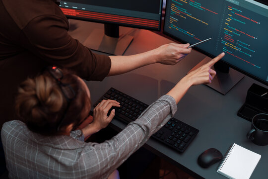 Top view of IT developers discussing with point to intelligent website development coder system running data online two screens information technology at neon light room at modern office. Infobahn.