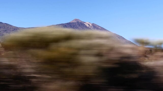 Teide Volcano with Rocky Landscape Under Blue Sky. View of the mountain from a fast-moving car.