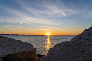 Piran, Slovenia - November 3, 2024: Sunset against the backdrop of a calm sea. The sun goes down behind the sea horizon.