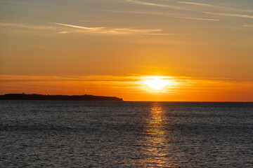 Obraz premium Piran, Slovenia - November 3, 2024: Sunset against the backdrop of a calm sea. The sun goes down behind the sea horizon.