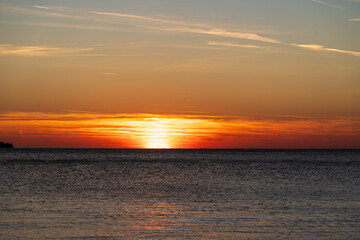 Piran, Slovenia - November 3, 2024: Sunset against the backdrop of a calm sea. The sun goes down behind the sea horizon.