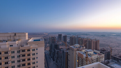 Cityscape of Ajman from rooftop before sunrise night to day timelapse. United Arab Emirates.