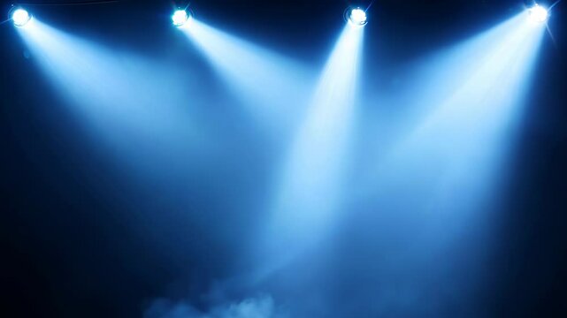 Dramatic blue spotlights pierce through atmospheric haze on dark stage. Powerful beams create ethereal light cones in smoky air, highlighting floating particles. Perfect for performance backgrounds.
