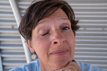 Woman with short brown hair and a silver earring winking at camera