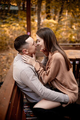 a young couple guy with a girl in autumn in a cafe in brown and orange tones on an outdoor terrace hugging and kissing, love or Valentine's day
