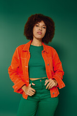 A vibrant young woman with curly hair showcases her joyful expression while standing against a...