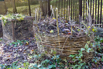 Compost bins for plant waste are set up in a garden to support eco-friendly recycling. Organic...