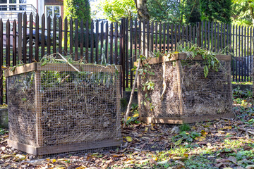 Compost bins for plant waste are set up in a garden to support eco-friendly recycling. Organic...