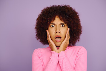 A young woman in pink clothing showcases her emotions, hands on her face, with a lively purple backdrop.