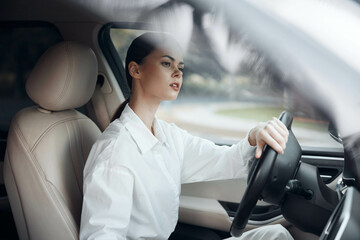 Woman driver inside car, hand on steering wheel, looking at camera a woman sits confidently in the driver's seat of a car, her hand resting on the steering wheel, gazing directly at the camera with a