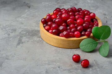 Cranberries in a wooden bowl on a dark background. Horizontal, free space.