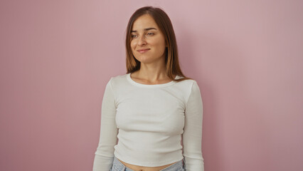 Obraz premium Attractive young woman with blonde hair wearing a white sweater, standing isolated against a pink wall background.